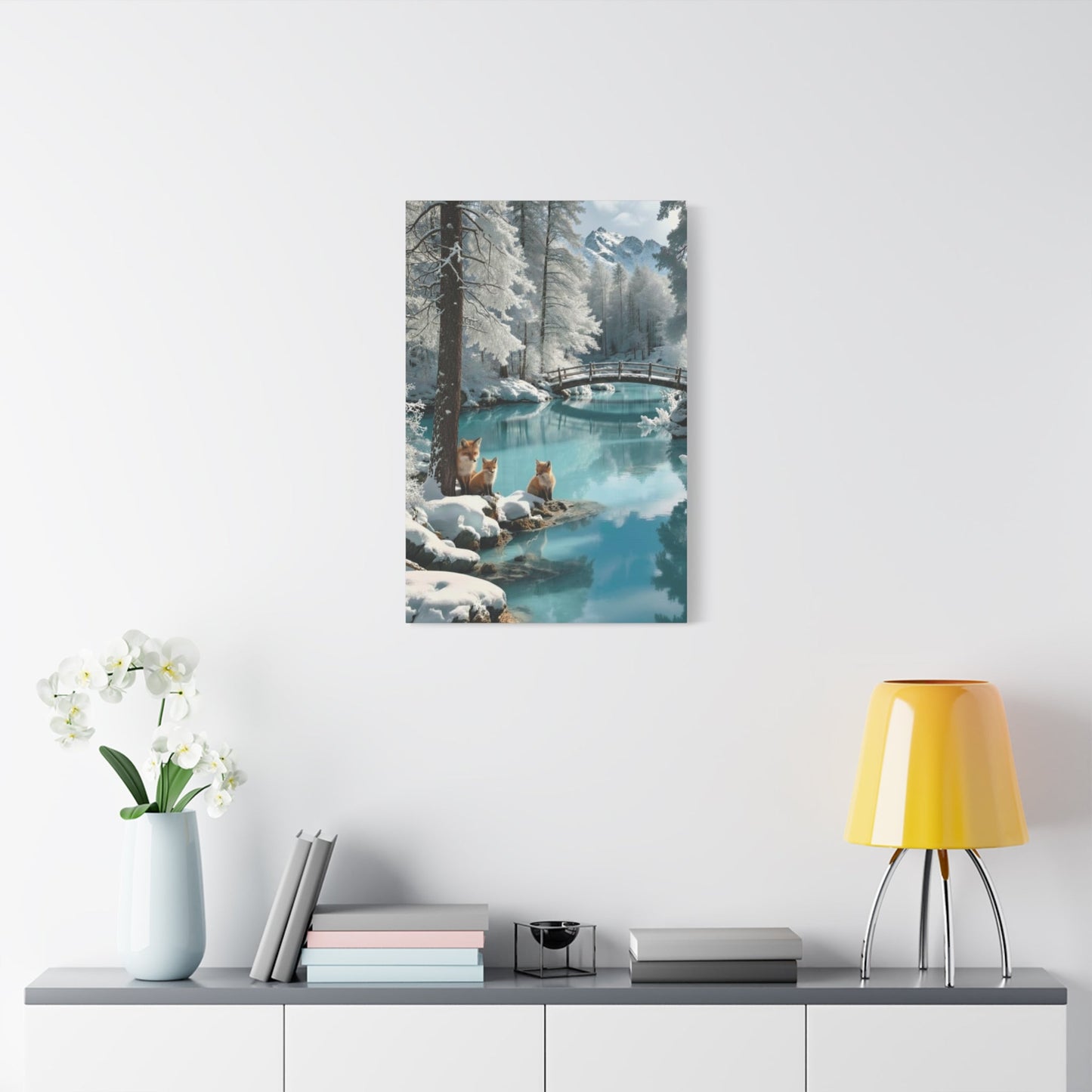 Canvas wall art featuring a winter landscape with two foxes by a snowy river under a bridge, displayed in a modern living space.