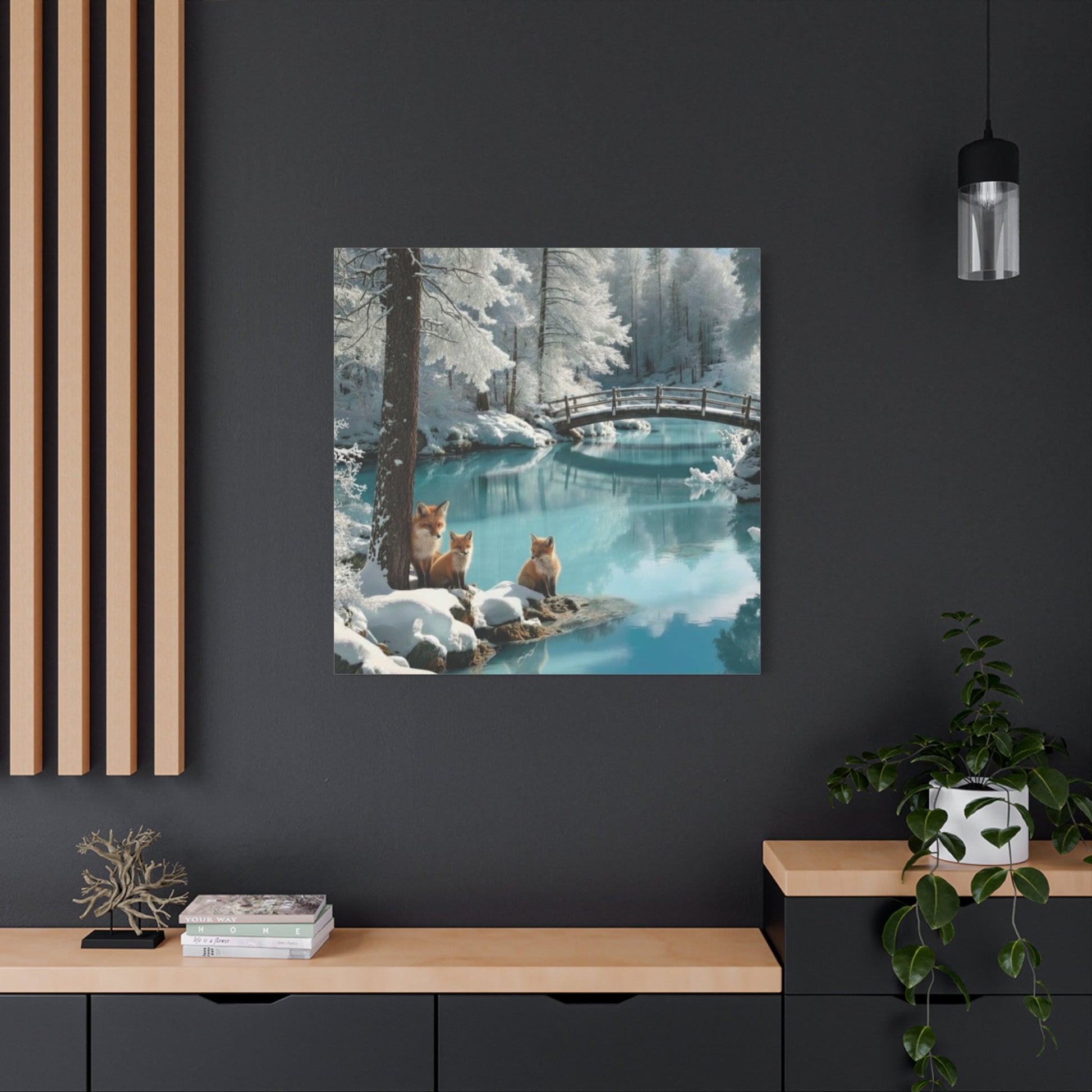 Canvas wall art of winter foxes by a snowy river with a wooden bridge in a cozy modern room